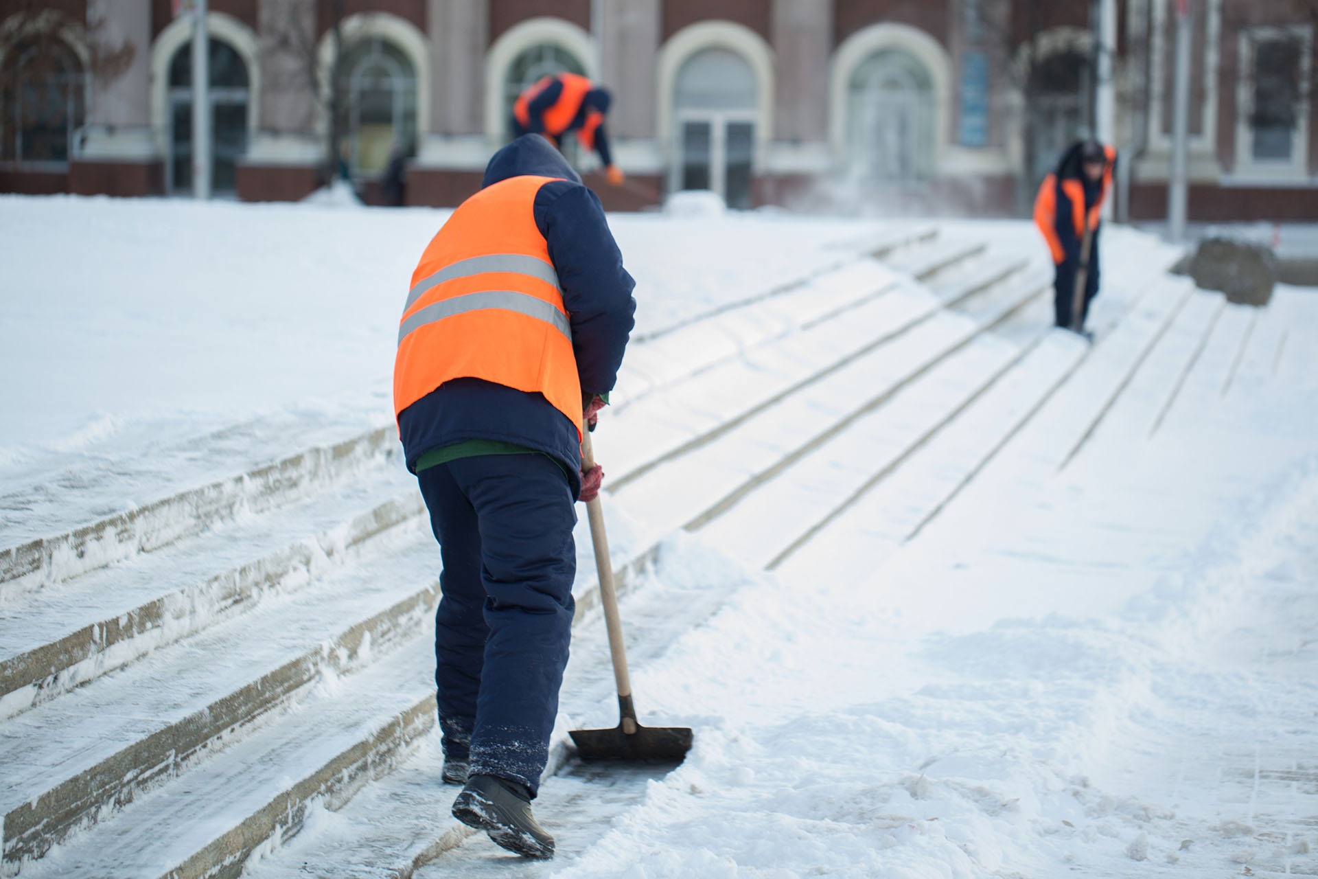 Workers sweep snow from road in winter, Cleaning road from snow